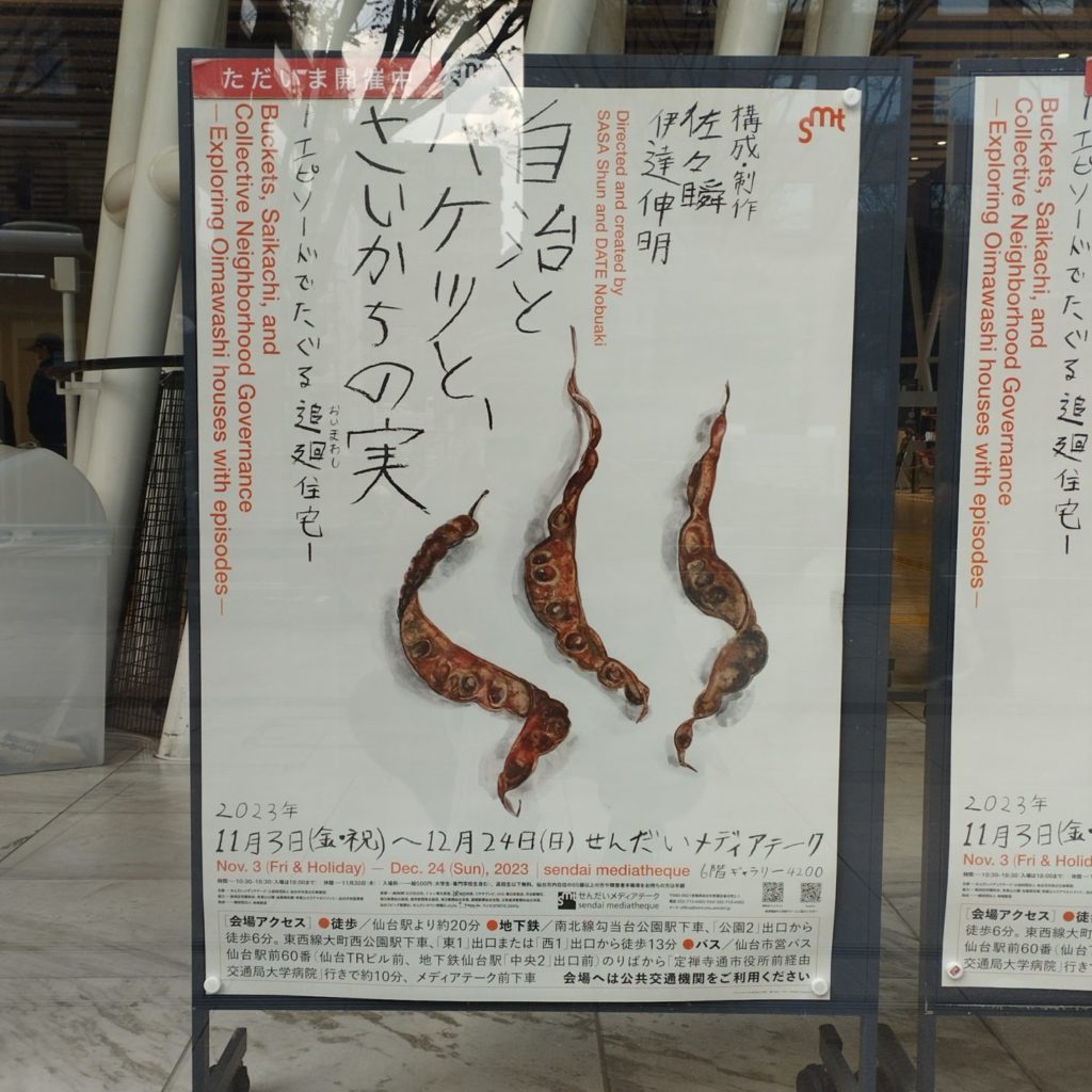 せんだいメディアテークの正面に掲示された、展覧会「自治とバケツと、さいかちの実」のポスター
